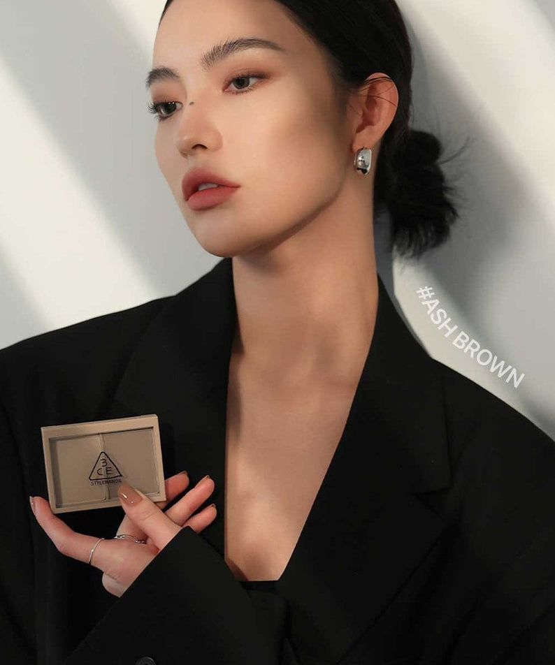 Maquillage 3CE Contour Shading de 3CE, maquillage de contour sur une femme en tenue noire, fond clair.