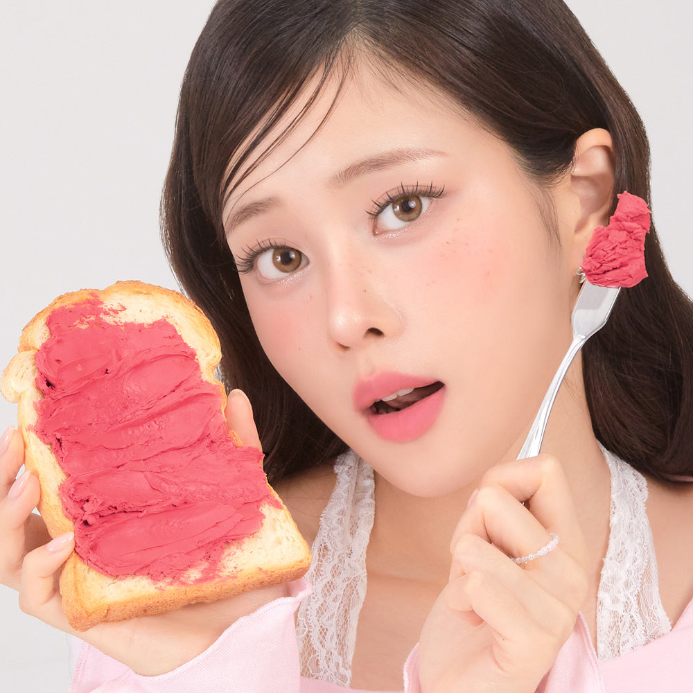 CORINGCO Topping Tip Velvet Lip Tint de CORINGCO : la teinte rose sur lèvres, avec une femme et du pain, fond clair.