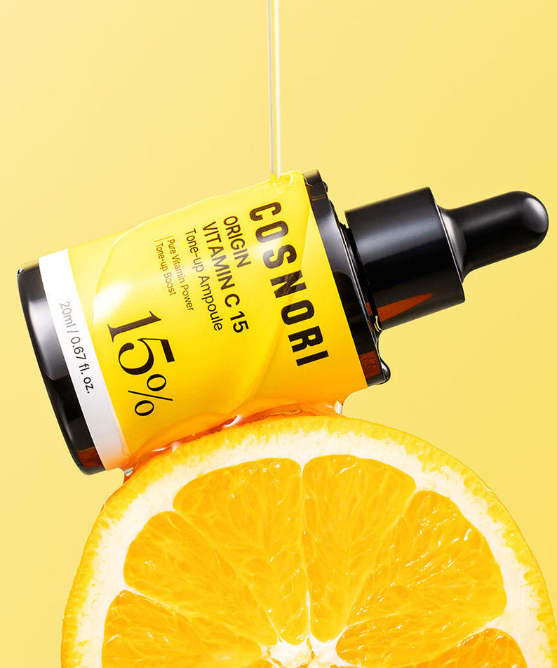 COSNORI Origin Vitamin C 15 Tone-Up Ampoule 20ml de la marque COSNORI, sur fond jaune, avec oranges tranchées.