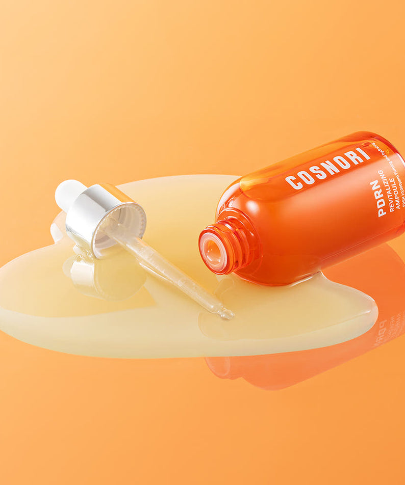 COSNORI PDRN Revitalizing Ampoule 50ml de COSNORI, flacon orange sur fond orange, sérum versé en gouttes
