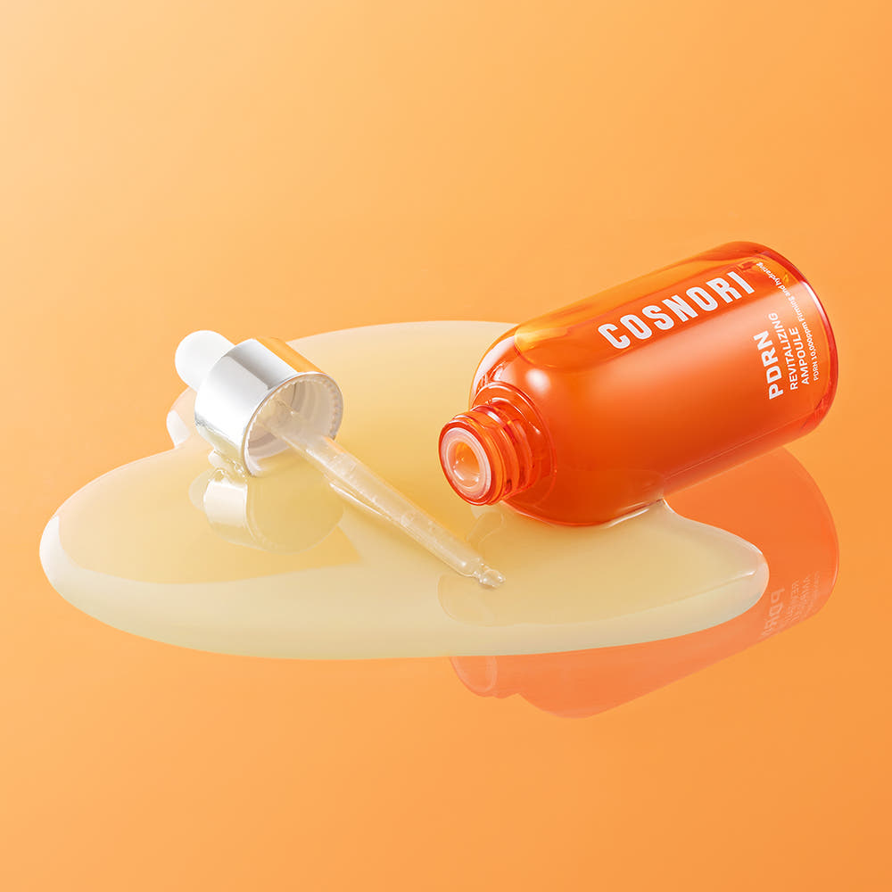 COSNORI PDRN Revitalizing Ampoule 50ml de COSNORI, flacon orange sur fond orange, sérum versé en gouttes