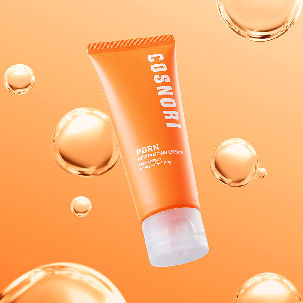 COSNORI PDRN Revitalizing Cream 70ml, crème dans un décor orange avec bulles dorées, flacon centré sur fond chaud.