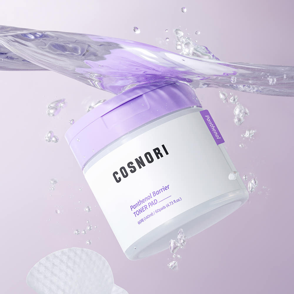 Décris l'image en français : COSNORI Panthenol Barrier Toner Pads 60 Sheets, flacon et pads violets avec éclaboussures d’eau.