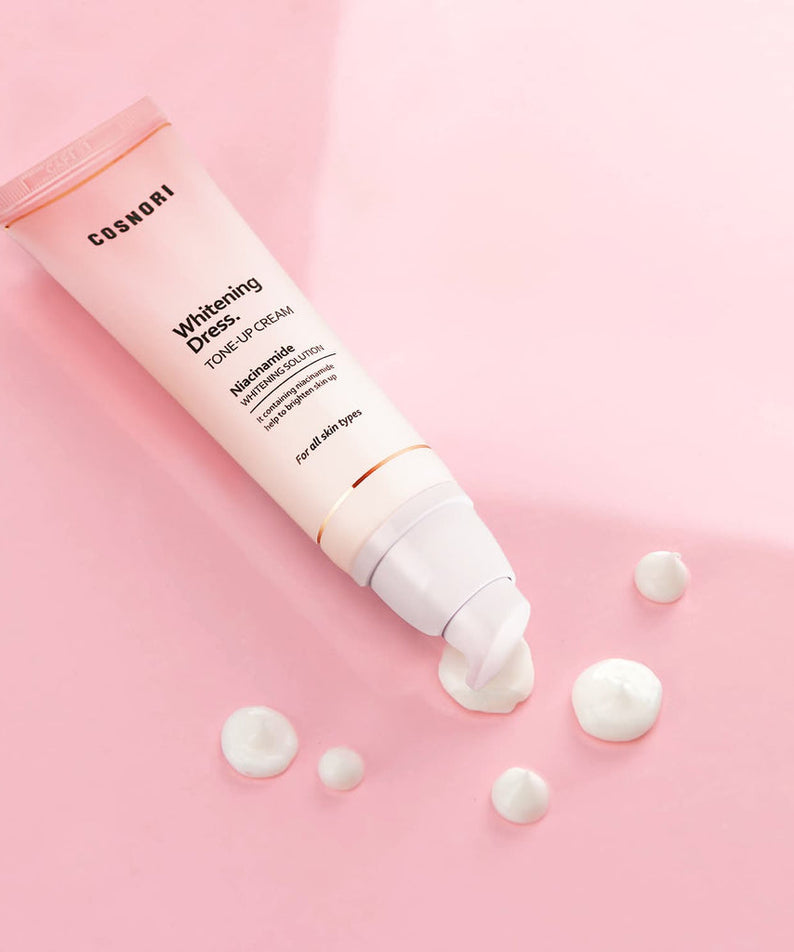 COSNORI Whitening Dress Tone-Up Cream 50ml, tube crème sur fond rose avec texture, contexte beauté en studio.