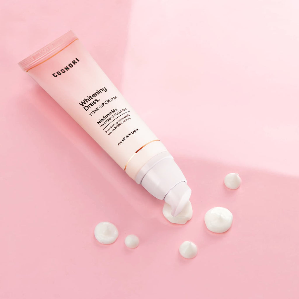 COSNORI Whitening Dress Tone-Up Cream 50ml, tube crème sur fond rose avec texture, contexte beauté en studio.