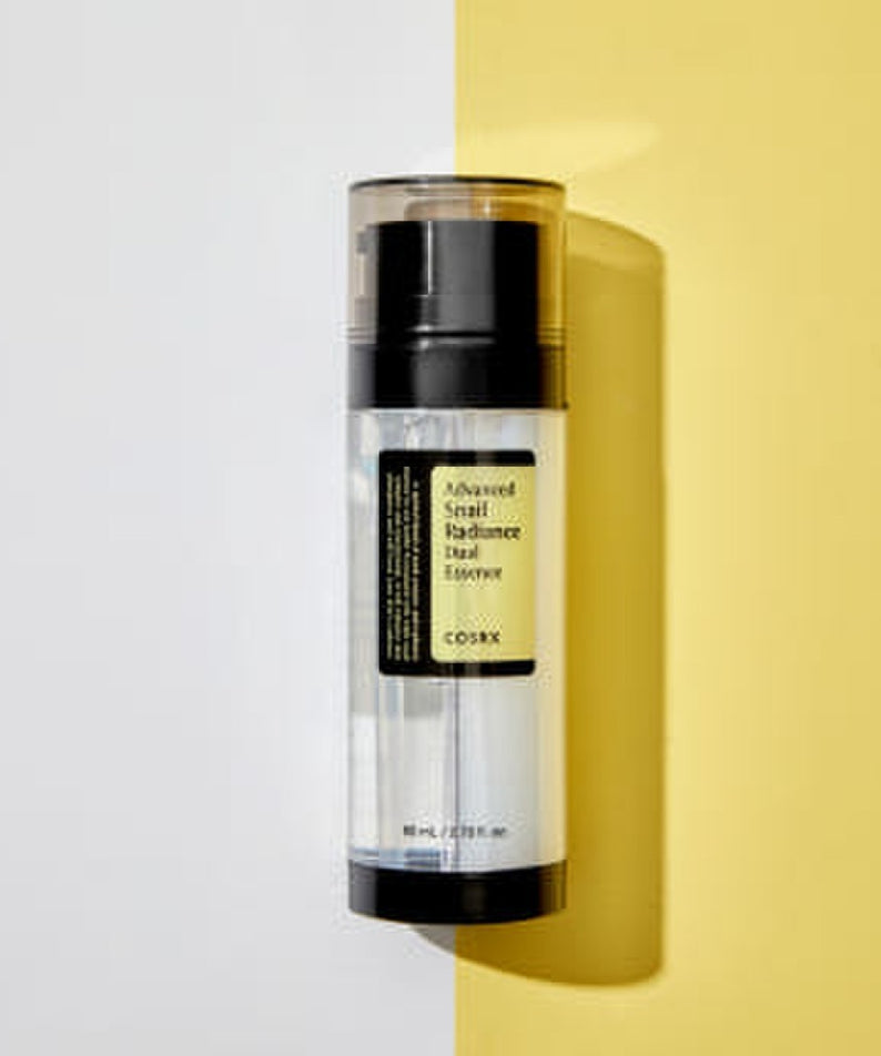 Décris l'image en français : COSRX Advanced Snail Radiance Dual Essence 80ml, bouteille COSRX sur fond jaune et blanc.