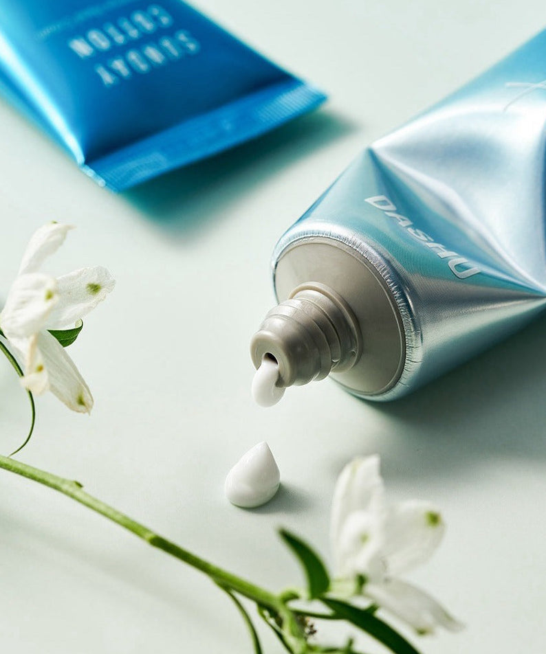 Crème pour les mains DASHU Perfume Hand Cream Sunday Cotton 50g avec fleurs blanches, tube ouvert et fluide sur fond vert.