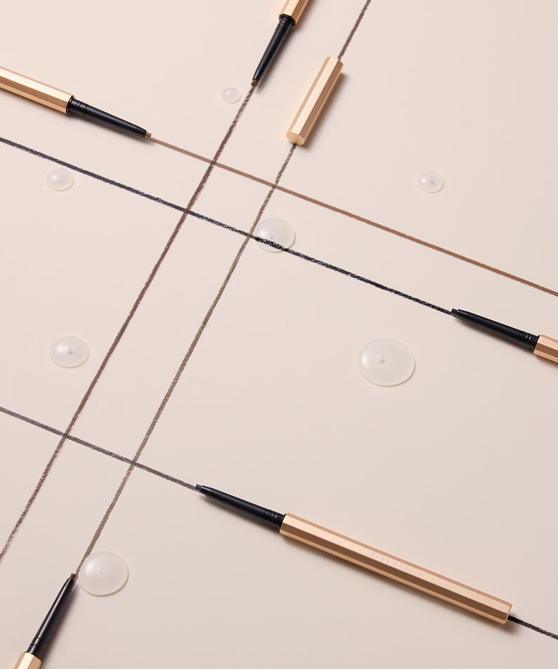 Stylos eyeliner dorés DEAR DAHLIA Perfect Desighning Eyeliner Pencil sur fond beige élégant