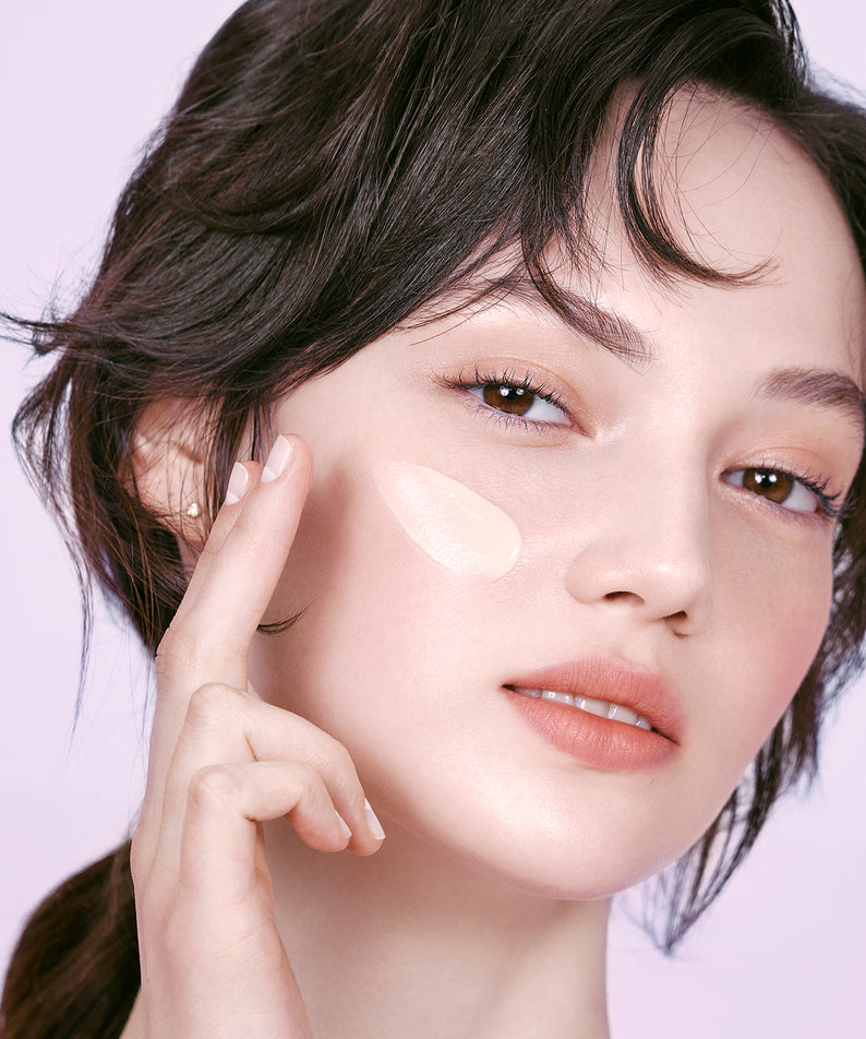 Femme appliquant DEAR DAHLIA Prime Layer Blurring Primer pour une peau parfaite et floutée.