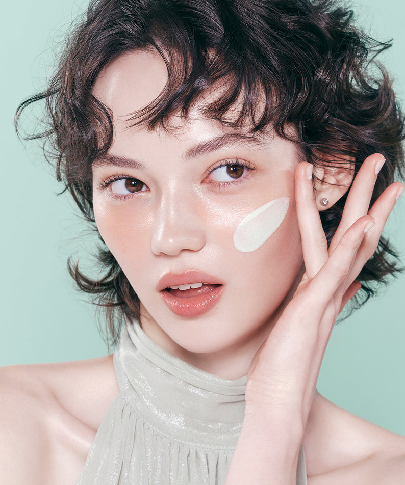 Femme appliquant le DEAR DAHLIA Prime Layer Correcting Primer sur son visage.