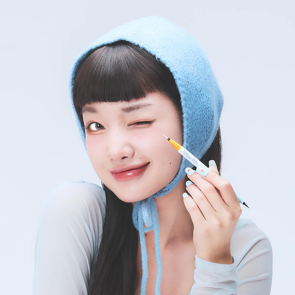DEAR MAY Tangerine Aegyo-sal Dual Liner de DEAR MAY, maquillage d’une femme avec eyeliner orange, tête et main en gros plan