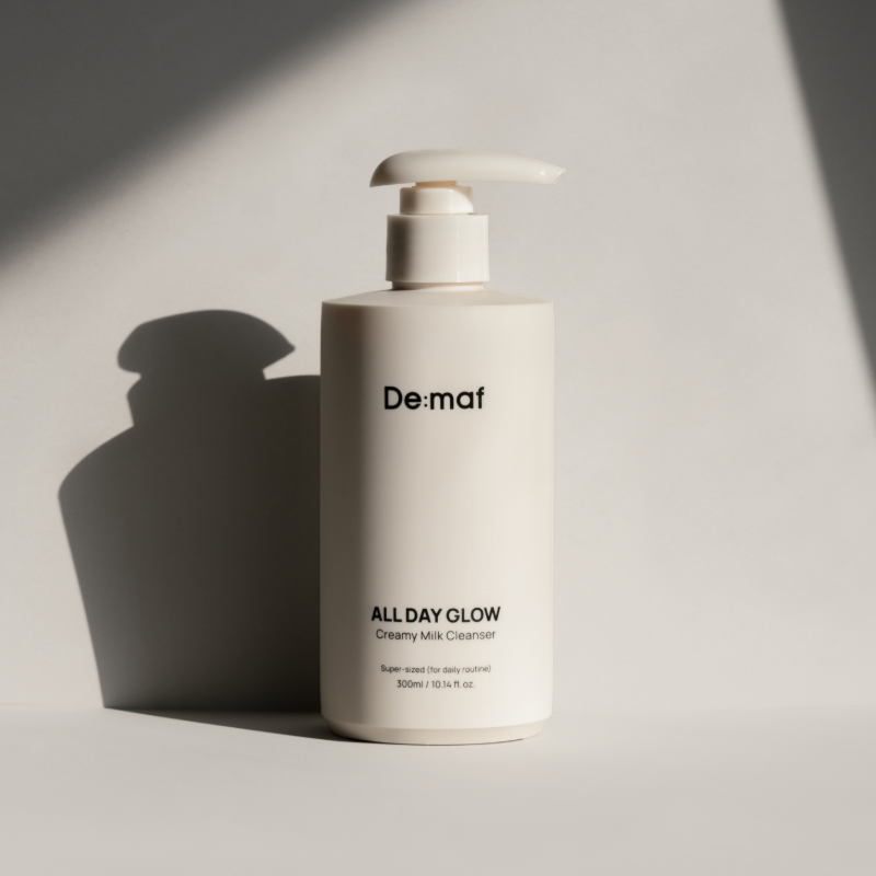 DE:MAF All Day Glow Creamy Milk Cleanser 300ml de De:mat, flacon blanc sur fond clair, lumière studio.