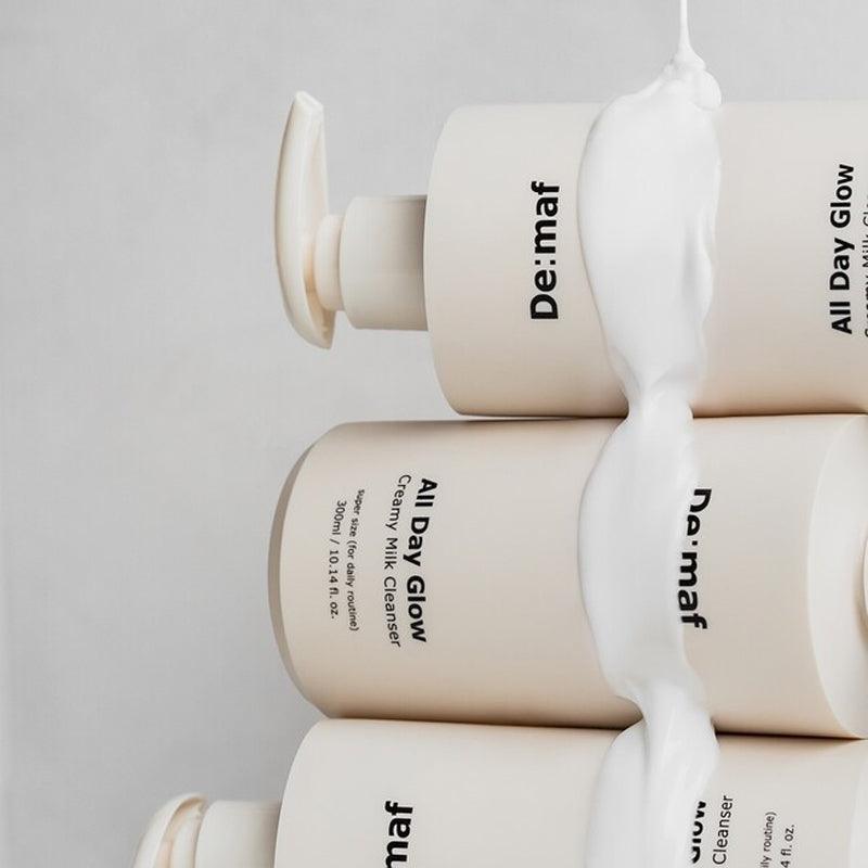 DE:MAF All Day Glow Creamy Milk Cleanser 300ml par De: maf, flacons crème, texture laiteuse sur fond clair.