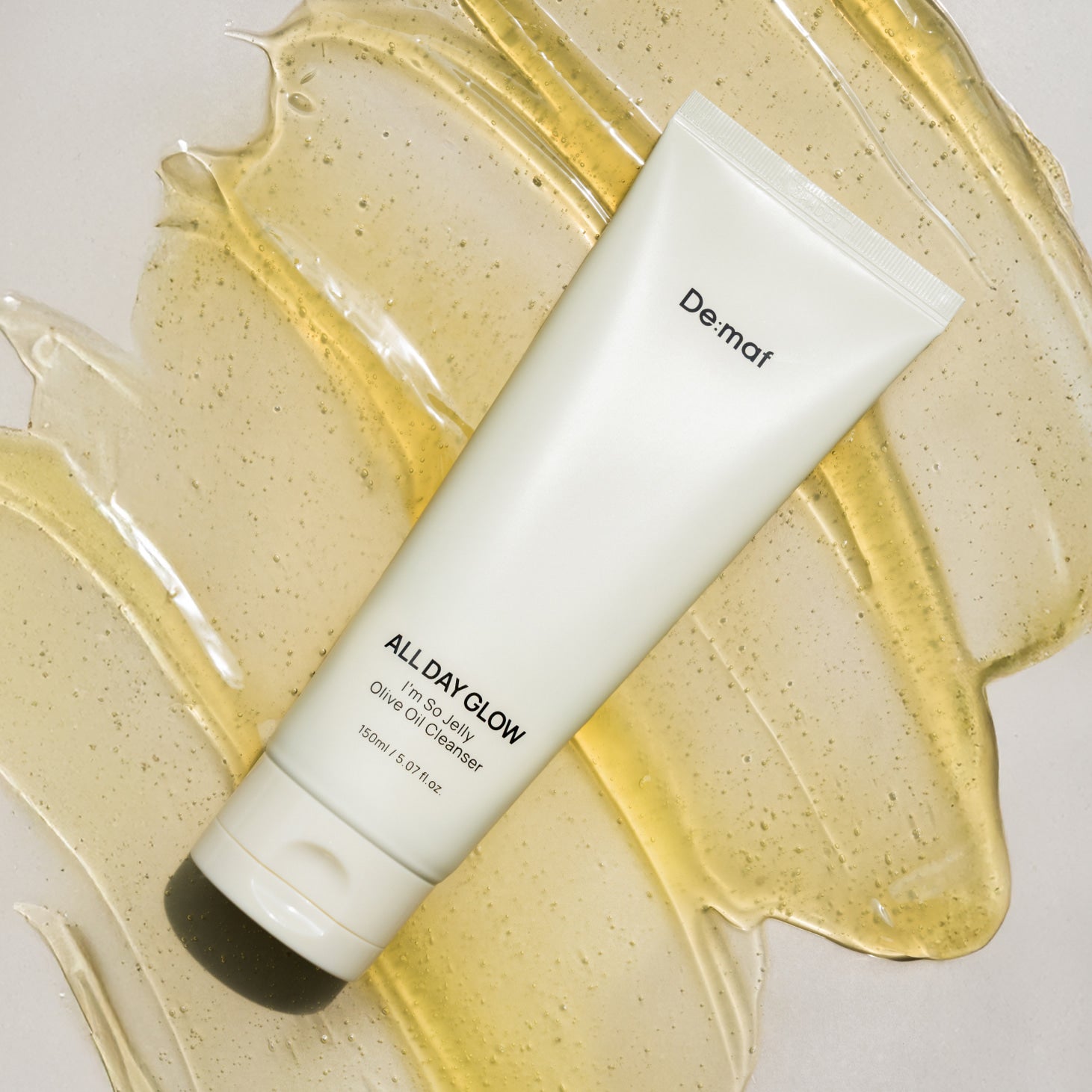 DE:MAF I'm So Jelly Olive Oil Cleanser 150ml De:mar sur fond lumineux, flacon et texture d’huile d’olive