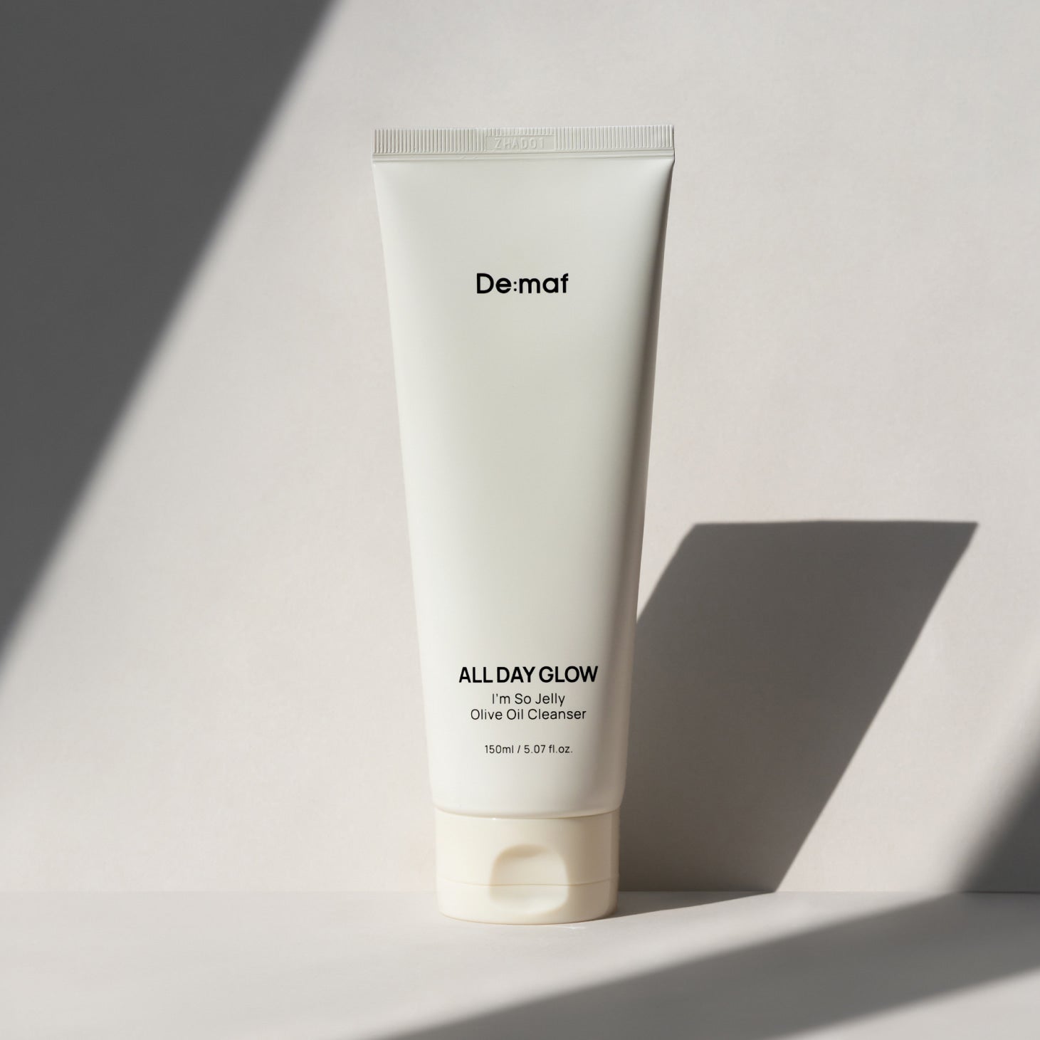 DE:MAF I'm So Jelly Olive Oil Cleanser 150ml De:maf, tube blanc sur fond clair, lumière douce.