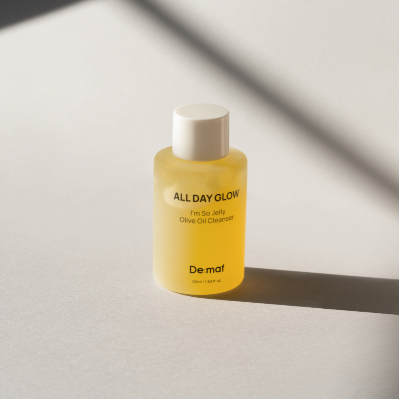 DE:MAF I'm So Jelly Olive Oil Cleanser 50ml, bouteille jaune Demaf, sur fond clair ensoleillé, style minimaliste