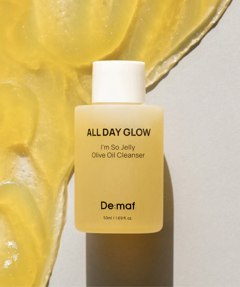 DE:MAF I'm So Jelly Olive Oil Cleanser 50ml De:màf, flacon sur fond jaune façon gelée, texture d’olive en arrière-plan