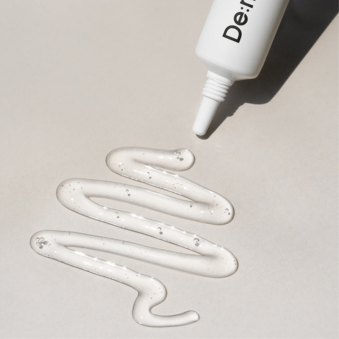 Décris l'image en français : DE:MAF SPOT Gel Soothing Pore-On Treatment Gel 10g, tube de marque, gel blanc sur fond clair.