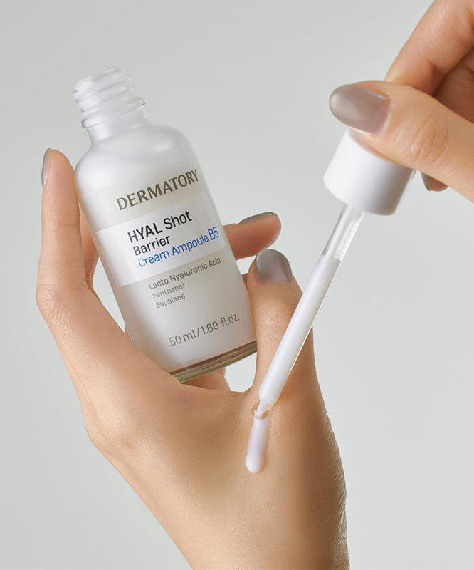 DERMATORY Hyal Shot Barrier Cream Ampoule B5 50ml, mains tenant le flacon et une pipette, fond clair, contexte cosmétique.