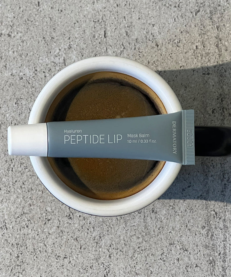 DERMATORY Hyaluronic Peptide Lip Keyring, tube crème pour lèvres sur fond béton, photo produit de la marque DERMATORY.