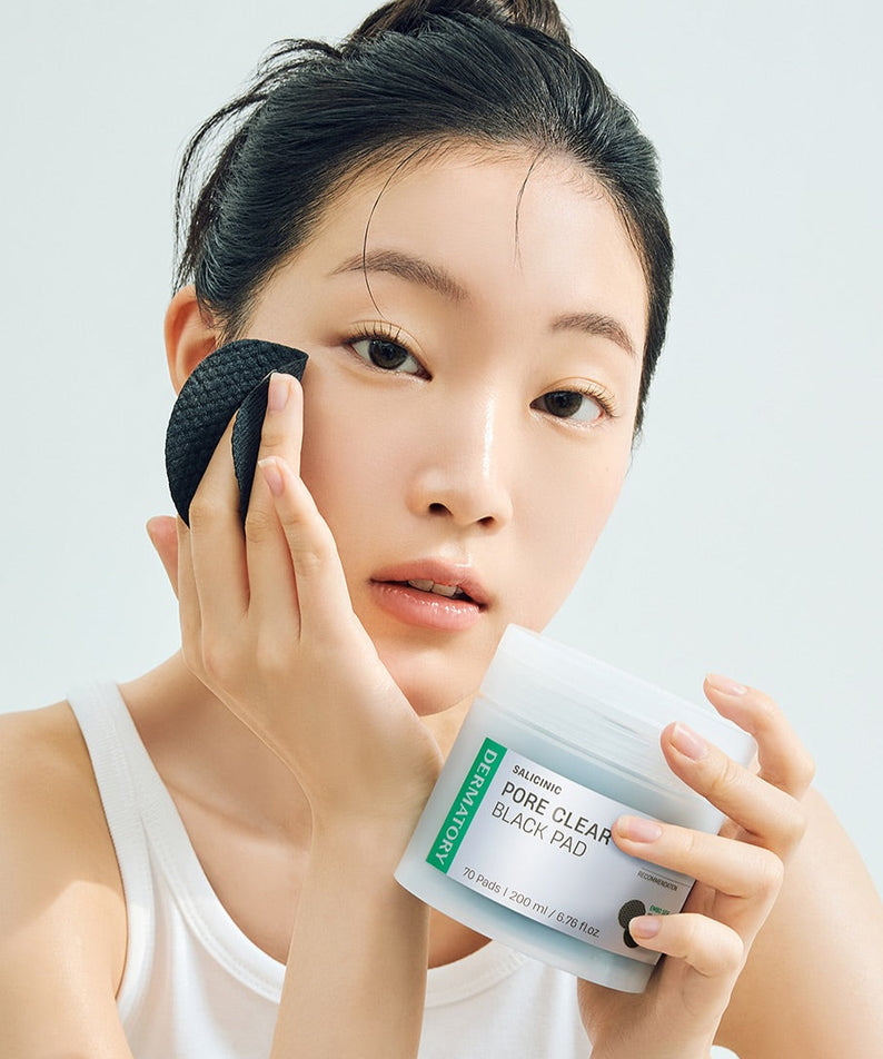 DERMATORY Salicinic Pore Clear Black Pad 70 Pads : femme applique un pad noir sur le visage, pot et packaging en gros plan.