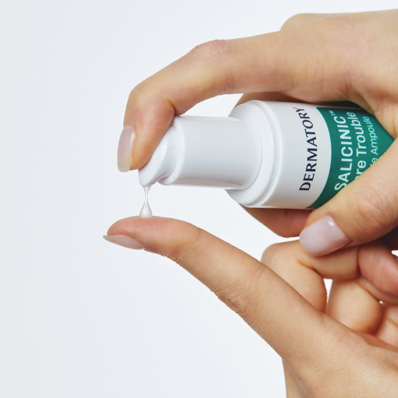 DERMATORY  Salicinic Pore Trouble Spicule Ampoule 50ml, main tenant le sérum goutte, fond clair, marque DERMATORY visible.