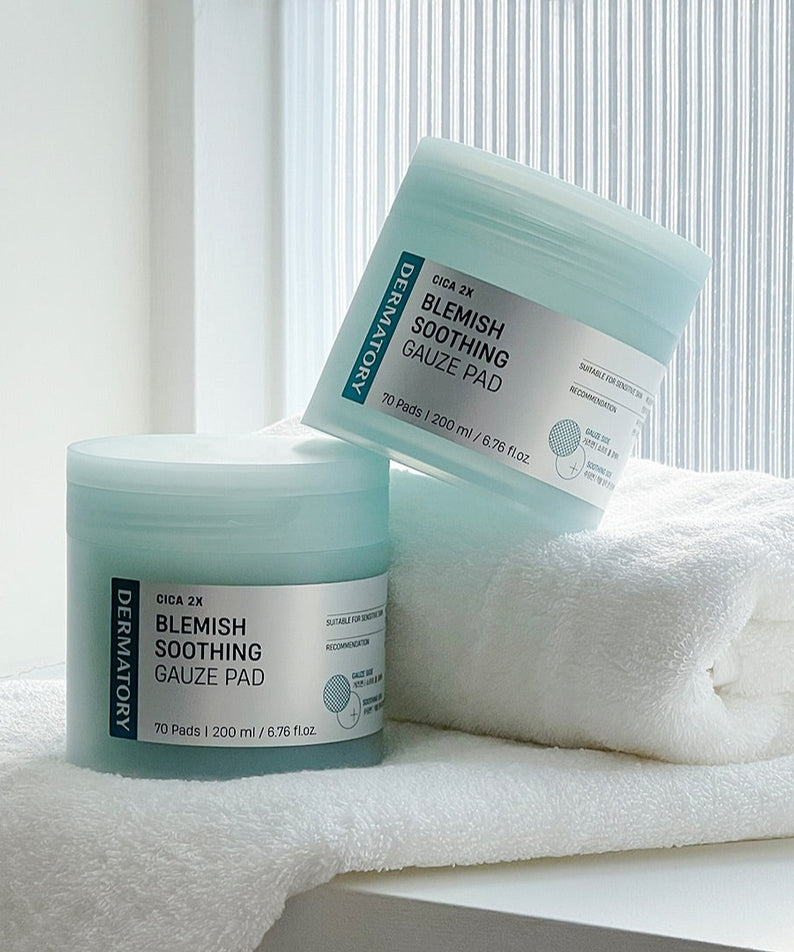 DERMATORY Cica Exosome Blemish Soothing Gauze Pad 70 Pads sur une étagère en verre avec des serviettes blanches.
