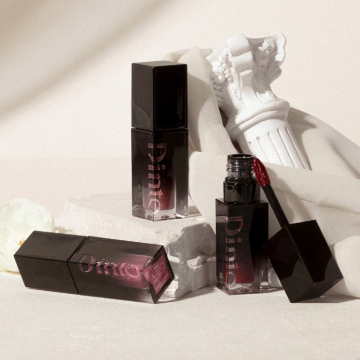 DINTO Blur-Glowy Lip Tint de la marque DINTO, flacons et applicateur sur fond clair, style maquillage lumineux.