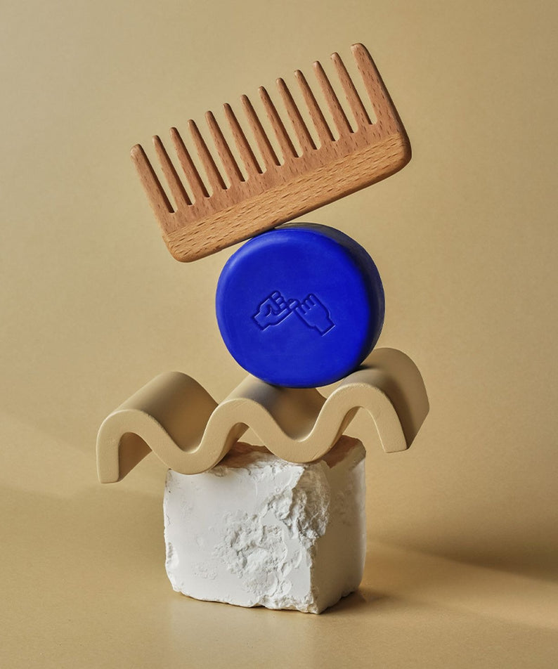 DONGGUBAT Correct Shampoo Bar Cooling avec un peigne en bois et des objets de décoration beige sur fond neutre.