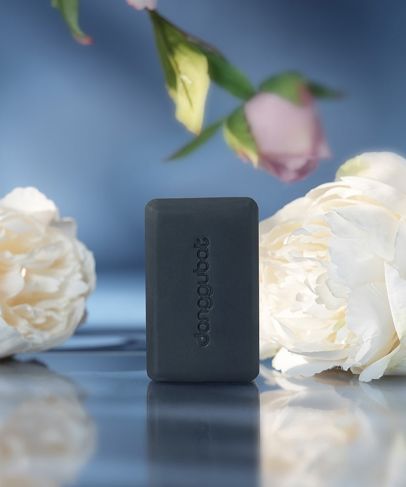 DONGGUBAT Field Blooming Perfume Shampoo Bar Repair 80g avec fleurs blanches en arrière-plan.
