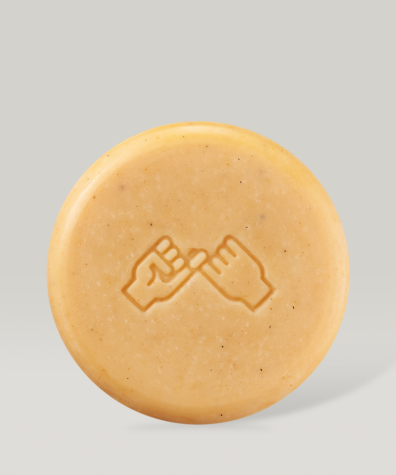 Barre de savon DONGGUBAT Field Face & Body Bar Lemongrass, forme circulaire, couleur beige, logo mains liées, parfum citronnelle