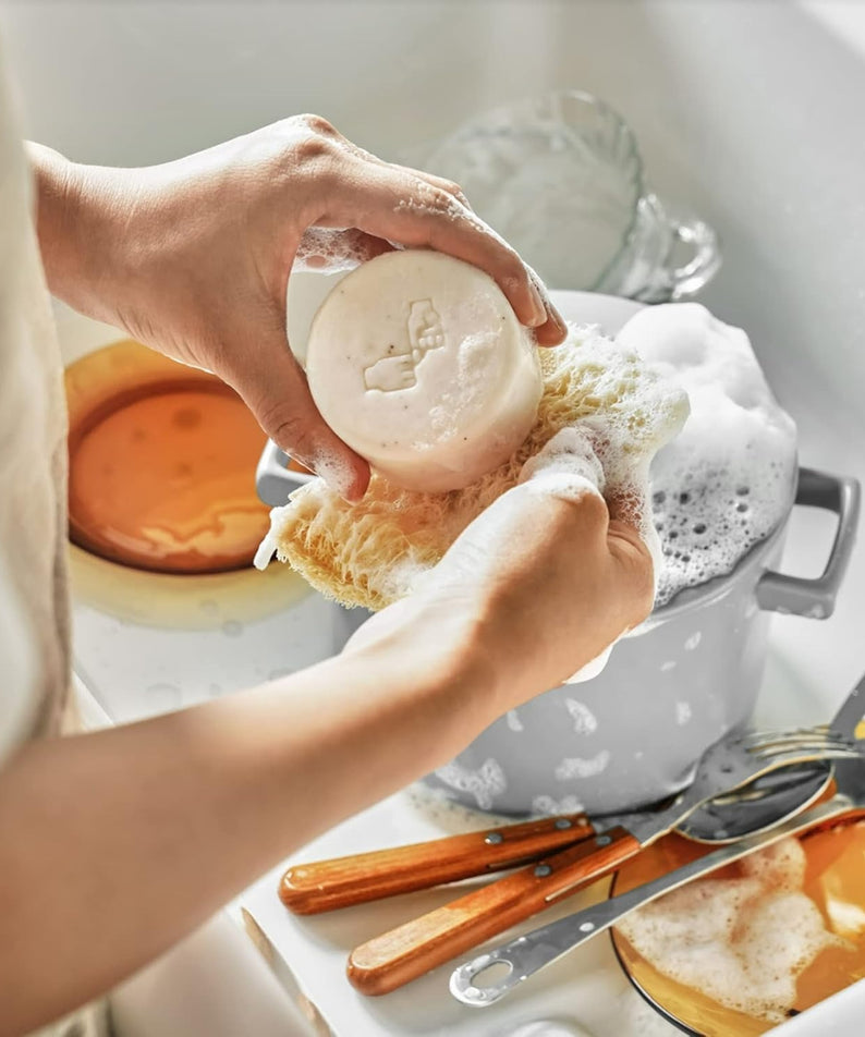 Décris l'image en français : DONGGUBAT Correct Dishwashing Washing Bar 500g de la marque DONGGUBAT, main tenant le savon.