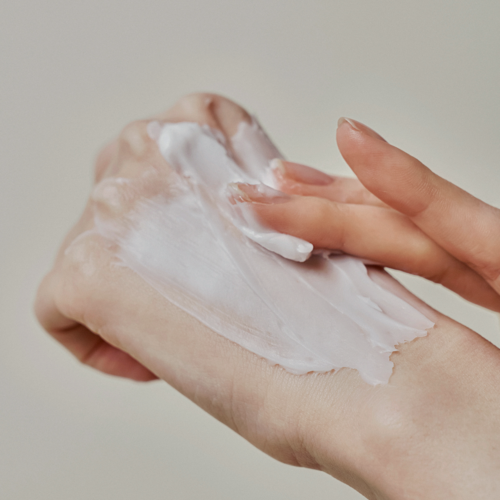 Main appliquant DONGGUBAT Correct Hand Cream Shea Butter, crème au beurre de karité, contexte soin beauté à domicile.