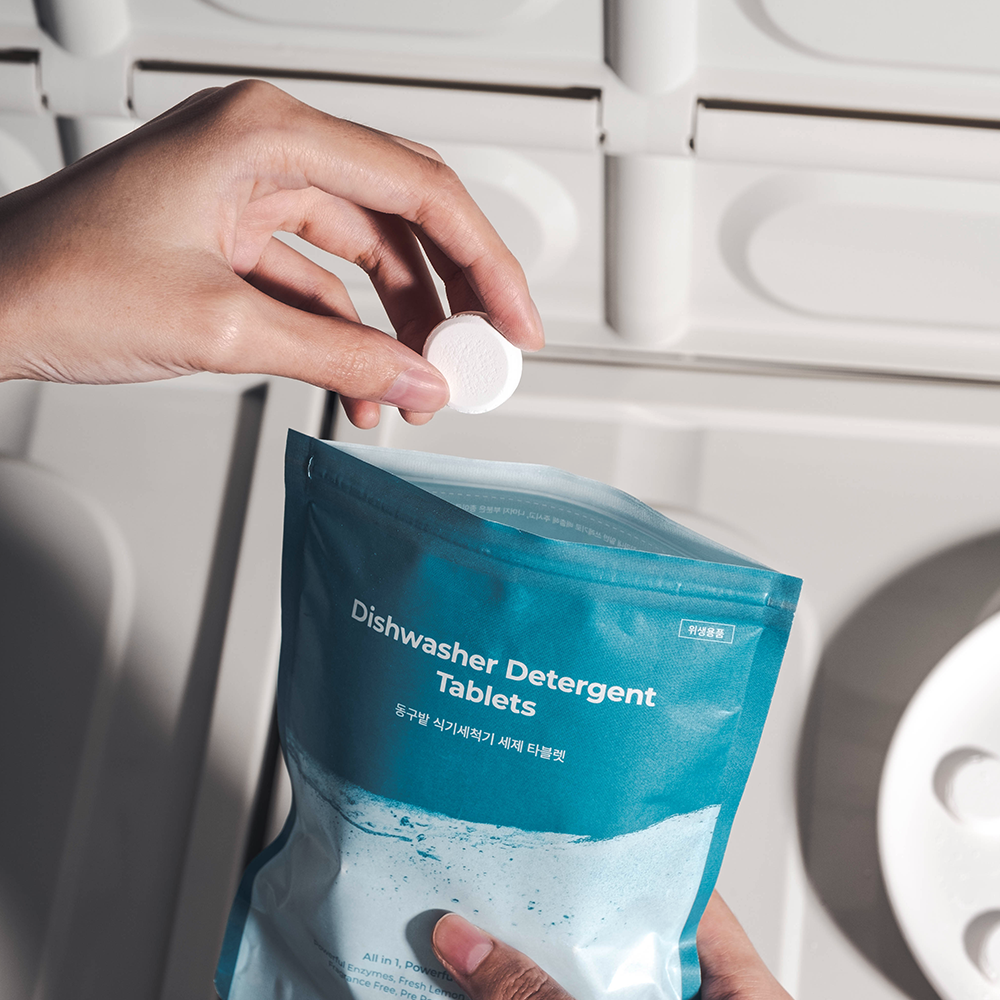 DONGGUBAT Dishwasher Detergent Tablets 60 240g : main plaçant une tablette dans un sac de détergent pour lave-vaisselle.