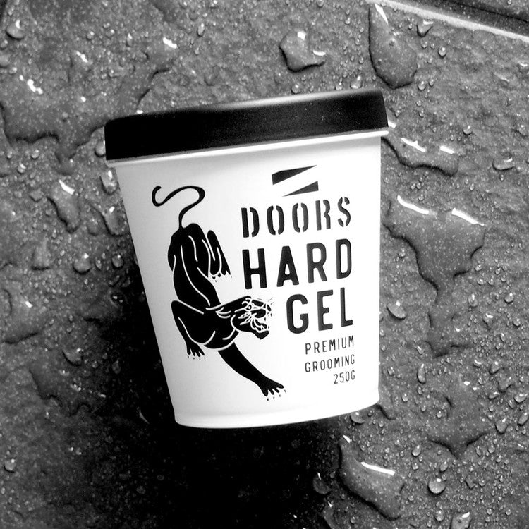 DOORS Hard Gel 250g sur fond béton mouillé, pot blanc avec logo DOORS, intérieur studio noir et eau