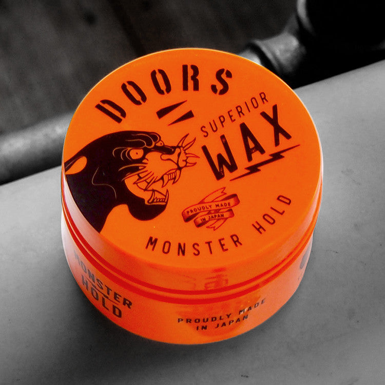 DOORS Superior Wax Monster Hold 80g, cire coiffante en pot orange DOORS, sur fond noir et chromé, gros plan.