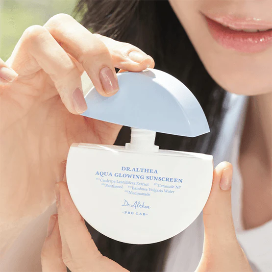 DR.ALTHEA Aqua Glowing Sunscreen 45ml : crème solaire hydratante appliquée, main et visage, contexte lumineux en extérieur.