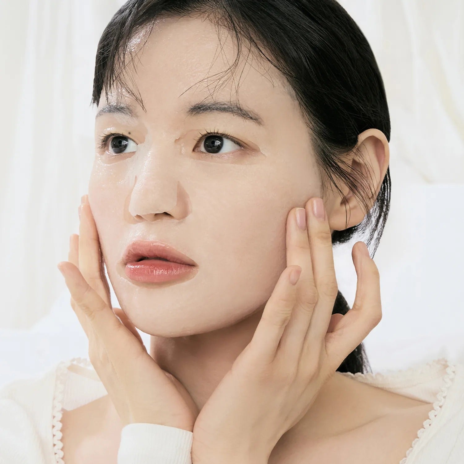 Décris l'image : DR.ALTHEA Cushion Veil Calming Mask (4ea), sur peau apaisée, visage de femme, mains en application.