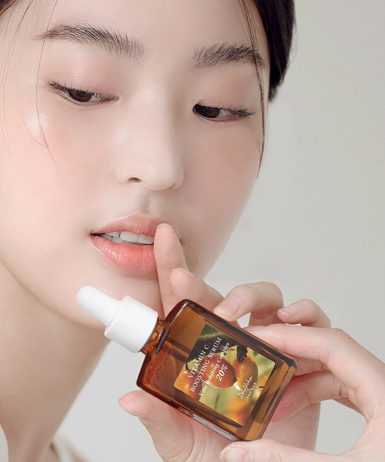 Femme appliquant DR.ALTHEA Vitamin C Boosting Serum 30ml sur son visage, image promotionnelle du produit en gros plan.