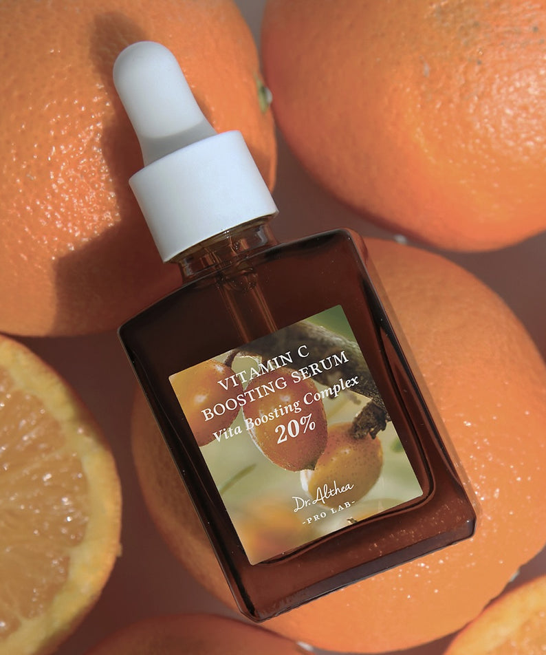 Sérum DR.ALTHEA Vitamin C Boosting Serum 30ml entouré d'oranges, flacon sur fond d'agrumes, amélioration de la peau éclatante