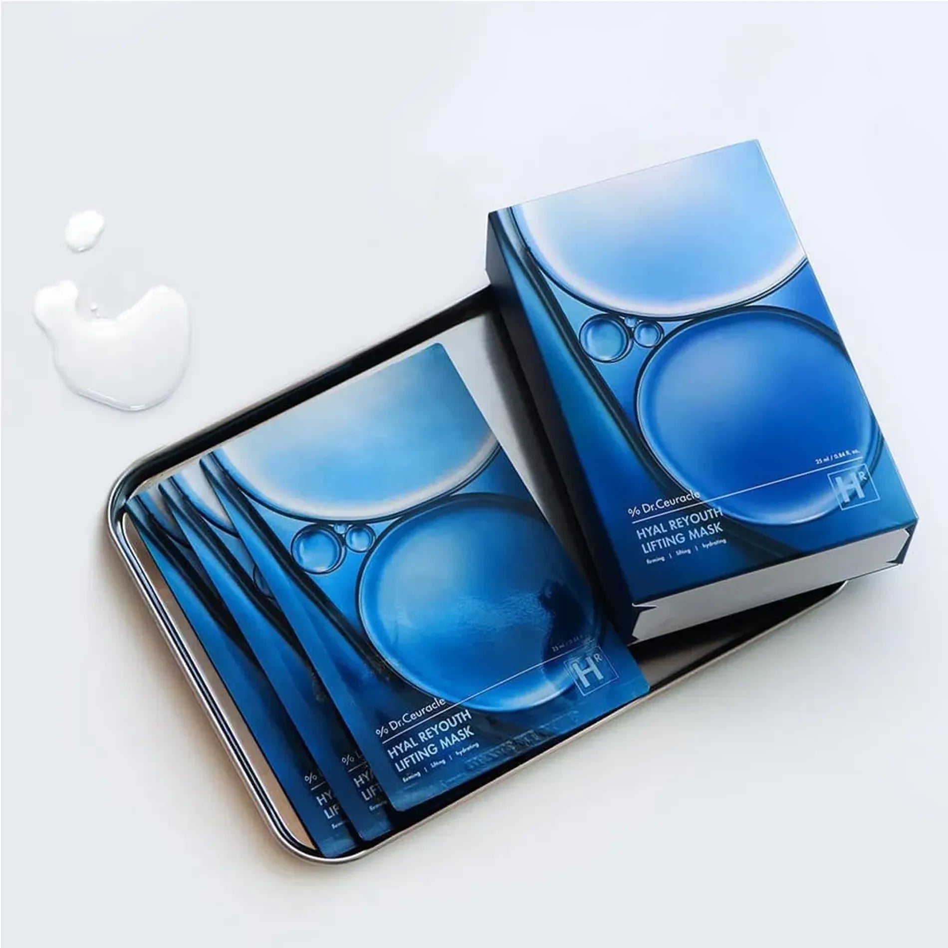 Décris l'image en français : DR.CEURACLE Hyal Reyouth Lifting Mask (10EA), marque sur coffret bleu, masques sur plateau.