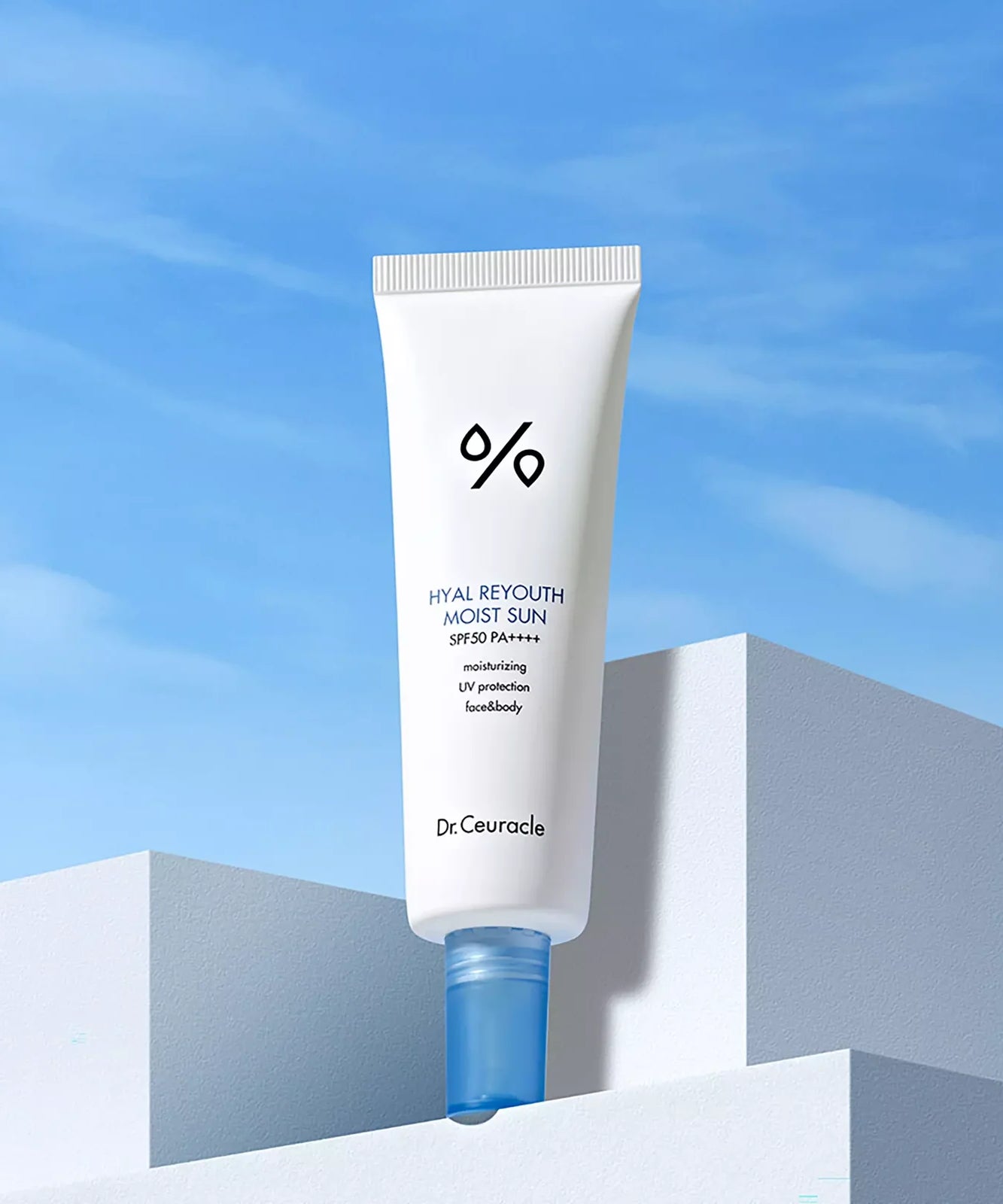 DR.CEURACLE Hyal Reyutsu Moist Sun SPF50+,PA++++ crème solaire hydratante présentée sur une surface minimaliste, ciel bleu en arrière-plan.