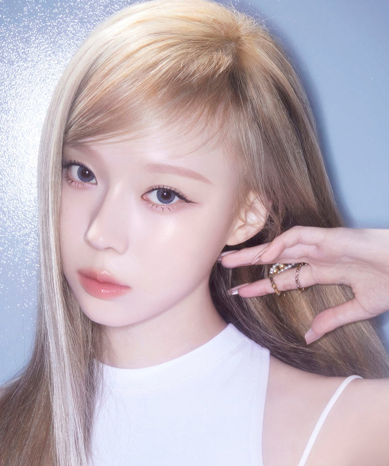 Jeune femme avec maquillage lumineux, utilisant ESPOIR BE GLOW FOUNDATION SPF27 PA++ pour un teint éclatant sur fond bleu.