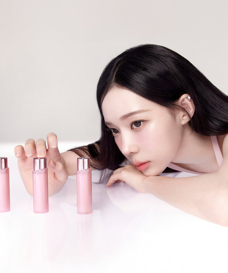 Modèle maquillage posant, ESPOIR Bare Glow Lip Balm à côté, marque ESPOIR en flacons roses sur fond clair.