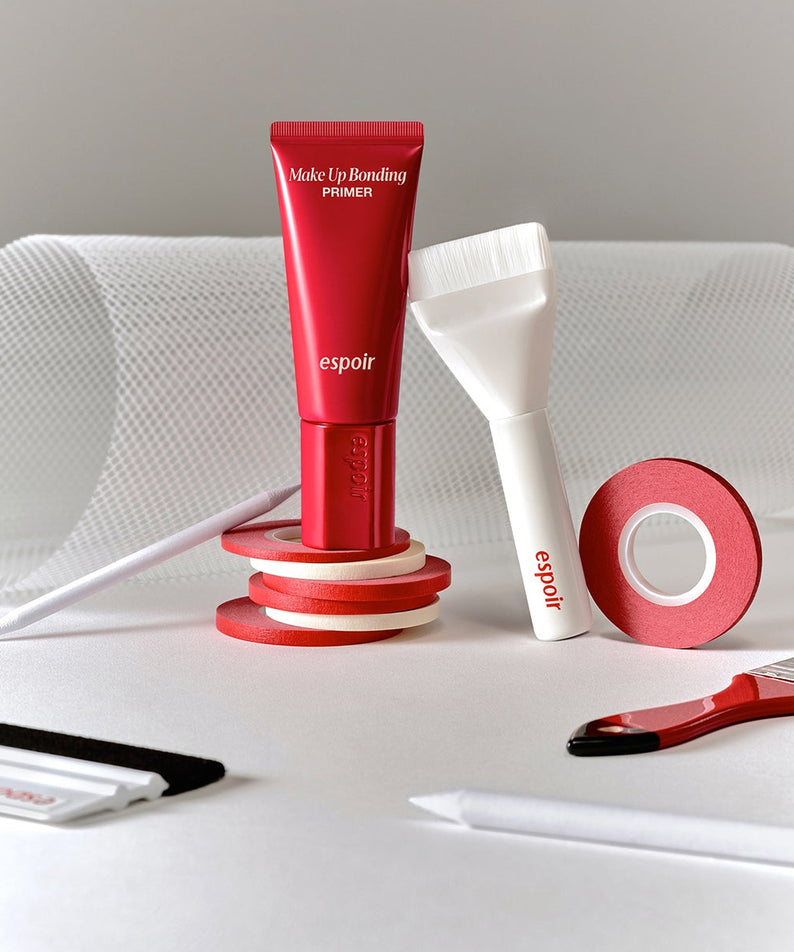 ESPOIR Make Up Bonding Primer rouge espoir sur fond maquillage, avec outils et ruban rouge, style studio