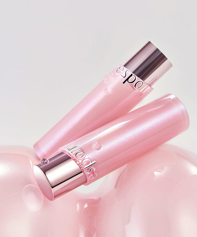 Deux baumes à lèvres roses ESPOIR Bare Glow Lip Balm sur fond rose doux et lumineux.