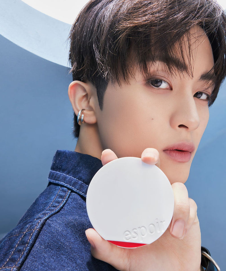 Homme tenant un ESPOIR Bevelvet Sebumcut Cooling Cushion avec un fond bleu, mettant en avant le produit cosmétique innovant.