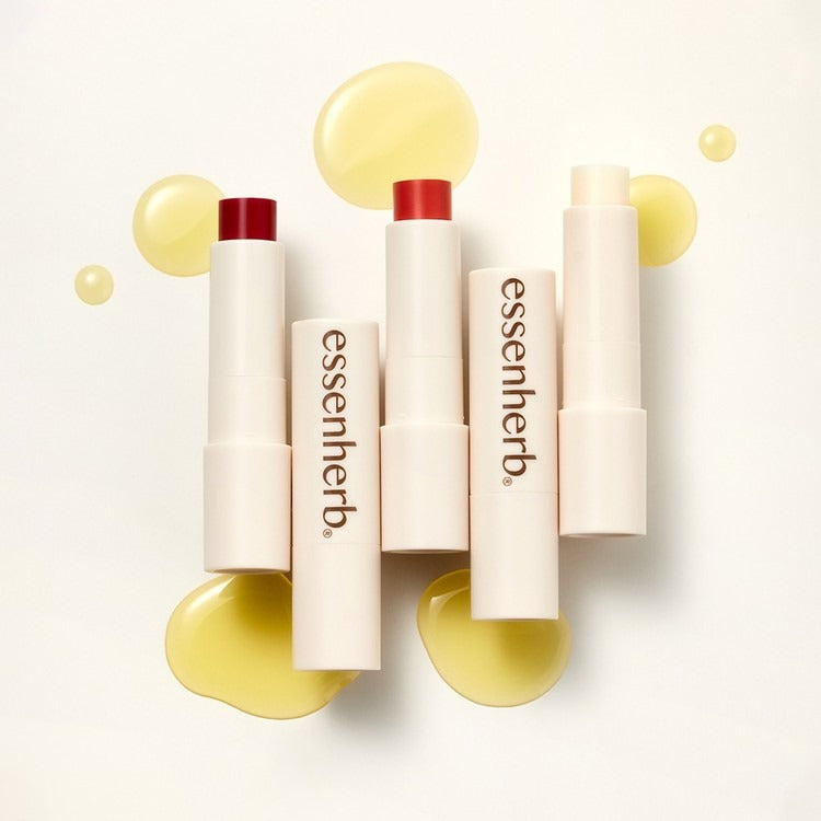 ESSENHERB  Jojoba Essentail Lip Balm 4g : tubes de baume à lèvres sur fond crème avec bulles dorées, photo produit