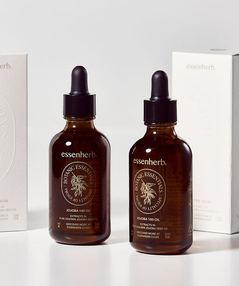 ESSENHERB Vegan Jojoba 100% Oil Unrefined Cold-Pressed 60ml, flacons en verre ambré devant des boîtes essenherb sur fond clair.