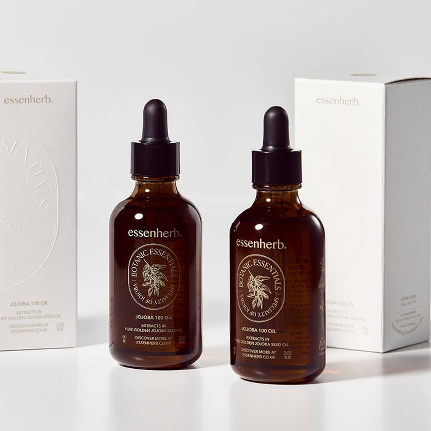 ESSENHERB Vegan Jojoba 100% Oil Unrefined Cold-Pressed 60ml, flacons en verre ambré devant des boîtes essenherb sur fond clair.